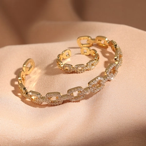 Golden hollow geometric jewelry set with zircon pave crystals on elegant champagne satin