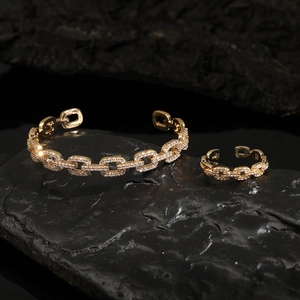 Macro shot of gold cuban chain jewelry set with cubic zirconia on black rock