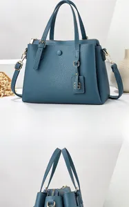 Detail of dark blue lychee grain leather tote bag with top handles and adjustable strap