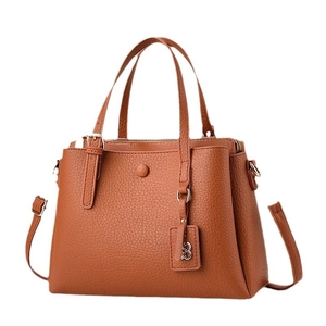 Brown litchi grain tote bag with dual handles and metal 'B' pendant on white background