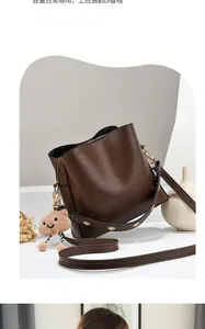 Detail of dark brown leather bucket bag with gold eyelet strap and plush charm