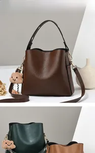 Close-up of three textured faux leather bucket bags in brown, green, and yellow hues