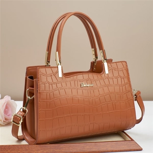 Detail of brown faux-crocodile texture tote with gold hardware and elegant top handles