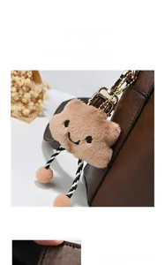 Detail of a brown plush cloud charm with embroidery on a textured leather bucket bag
