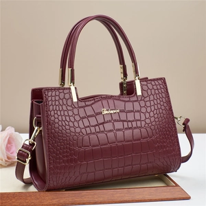 Detail of burgundy crocodile pattern leather tote with golden logo and double handles