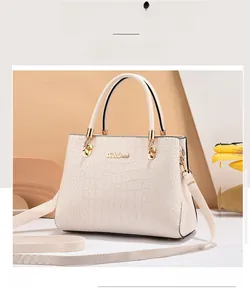 Detailed shot of white crocodile pattern handbag with gold hardware and brand logo