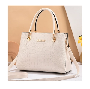 Detailed close-up of cream crocodile pattern tote bag with golden logo and texture