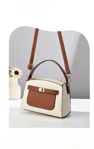 Détail du sac à main en cuir grainé crème avec bandoulière brune et fermoir tournant doré