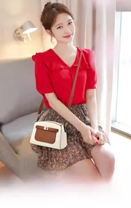 Sac bandoulière en cuir de vachette beige et marron porté par un mannequin en intérieur