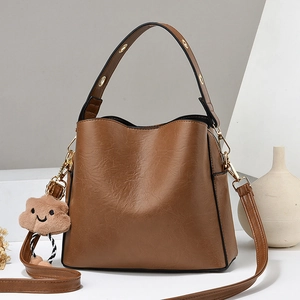 Brown leather bucket handbag with a plush cloud charm and detachable shoulder strap