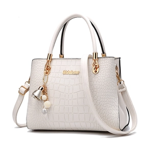 White crocodile embossed handbag with gold logo and elegant pearl floral bag charm