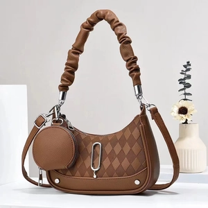 Detailed shot of brown quilted tote bag with ruffled handles and round coin purse