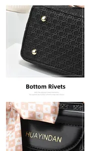 Detail of black woven texture handbag featuring gold bottom rivets and logo branding