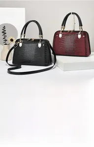 Detail of lizard-pattern embossed leather tote bag showing dual handles and gold hardware