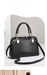 Detail of black lizard embossed PU leather handbag with gold-tone hardware and straps