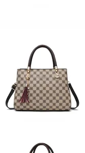 Vue de face du sac cabas à damier marron avec logo doré et pendentif pompon rouge