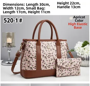 Détail du sac cabas beige à motif cerise, poignées en cuir marron et pendentif fleur