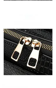 Detail of premium golden two-way metal zippers on a black lizard pattern handbag