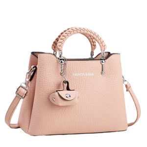 Litchi pattern crossbody bag with woven handle and mini pendant on white background