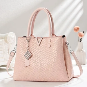 Detail shot of the pink embossed leather bag featuring a metal V-logo and chic charm