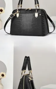 Close-up of black crocodile pattern faux leather handbag with golden metal hardware detail