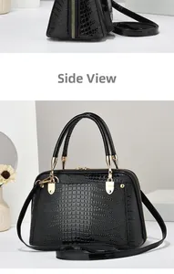 Close-up of black lizard pattern leather handbag with gold zipper and dual handles