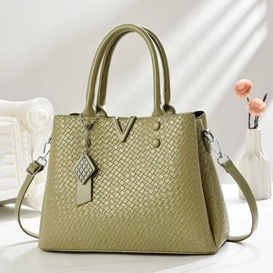 Detail of dark green woven texture leather bag with gold V-shape buckle and tassel charm