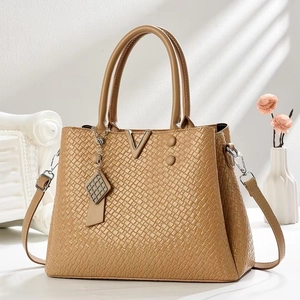 Detail of khaki tote bag with square embossed texture and golden V-shaped metal logo