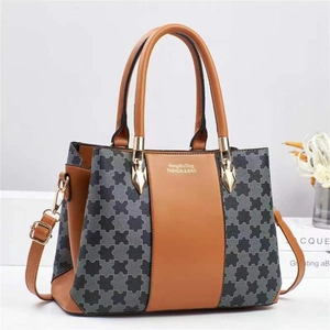 Detail of color-block leather handbag showing gold logo branding and textured fabric panels