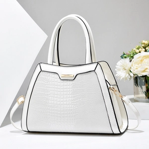 Detail of white crocodile texture tote bag with golden hardware and floral decor
