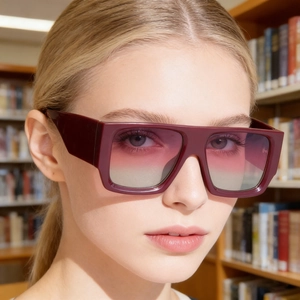 Close-up of oversized burgundy square sunglasses with gradient lenses on a female model