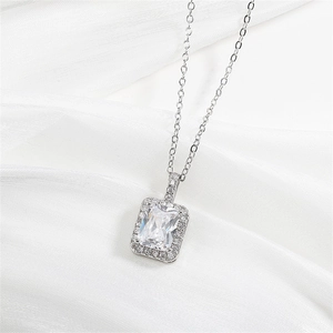 Silver necklace with emerald cut clear zircon pendant on elegant white silk background