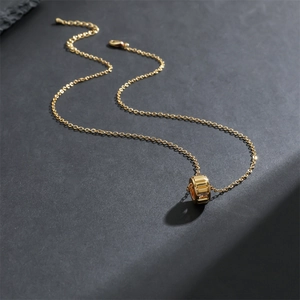 Collier cylindre plaqué or minimaliste avec zircons étincelants sur fond en pierre