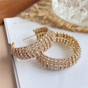 Goldene breite Creolen mit funkelnden Strasssteinen in eleganter Kulisse