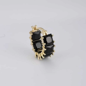 Close-up of golden hoop earrings featuring four square-cut black zircon stone settings