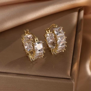 Close-up of gold hoop earrings with sparkling square-cut cubic zirconia in prong setting