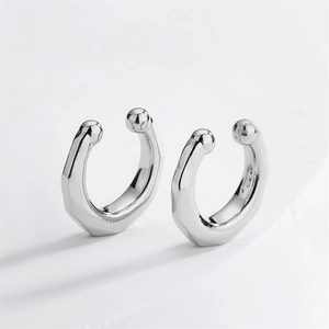 Detailed view of silver irregular geometric ear clips with spherical ends and faceted texture