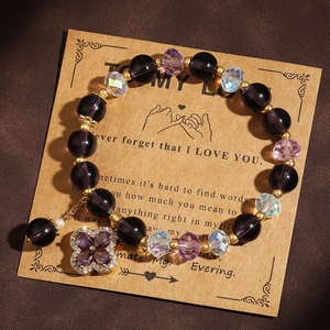 Detail of purple crystal beaded bracelet with clover charm on elegant greeting card