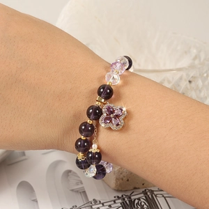 Close-up of purple crystal beaded bracelet with sparkling clover charm detail