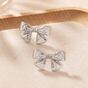 Boucles d'oreilles nœud en argent poli avec texture 3D sur plateau en bois