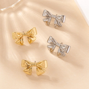 Détail macro de boucles d'oreilles nœuds en or et argent avec texture de soie polie