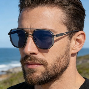 Close-up of men's square frame sunglasses with double bridge on a model by the sea