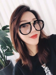 Detail of black oversized sunglasses with golden bow hardware on a female model