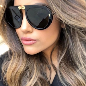 Detail of oversized black sunglasses with a golden bow-knot metal bridge accent