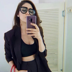 Detail of oversized folding sunglasses with rhinestone accents and striped blazer