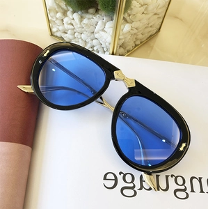 Detail of black folding sunglasses with blue lenses and gold metal spiked temple tips