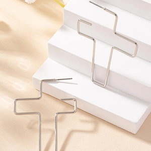 Modische silberne hohle Kreuzohrringe auf einem minimalistischen weißen Podest