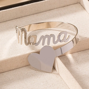 Bracelet manchette argenté avec motif mama et cœur sur un plateau à bijoux