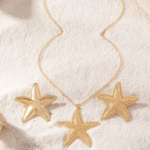 Macro view of golden starfish jewelry set with textured finish on a white sandy beach