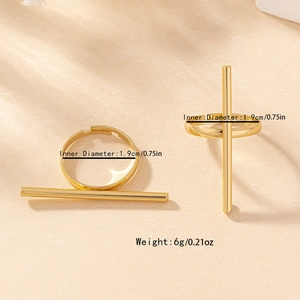 Minimalist geometric gold bar ring set with polished linear design on a cream surface